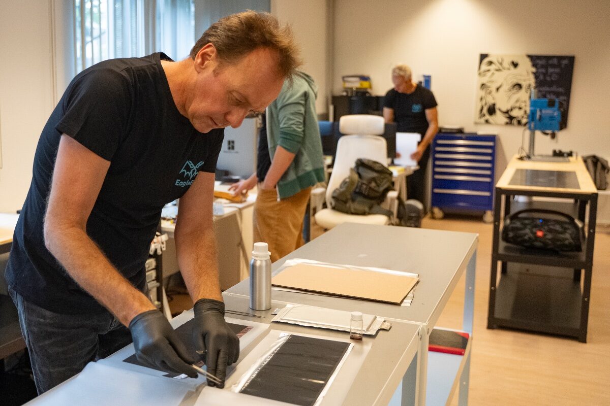 Een medewerker van Eaglebat werkt met een pincet aan een flinterdunne batterij.