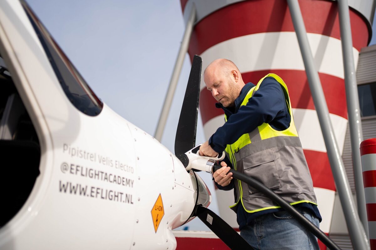 Man in geel hesje is een vliegtuig aan het aansluiten op het laadnetwerk van NRG2flr.